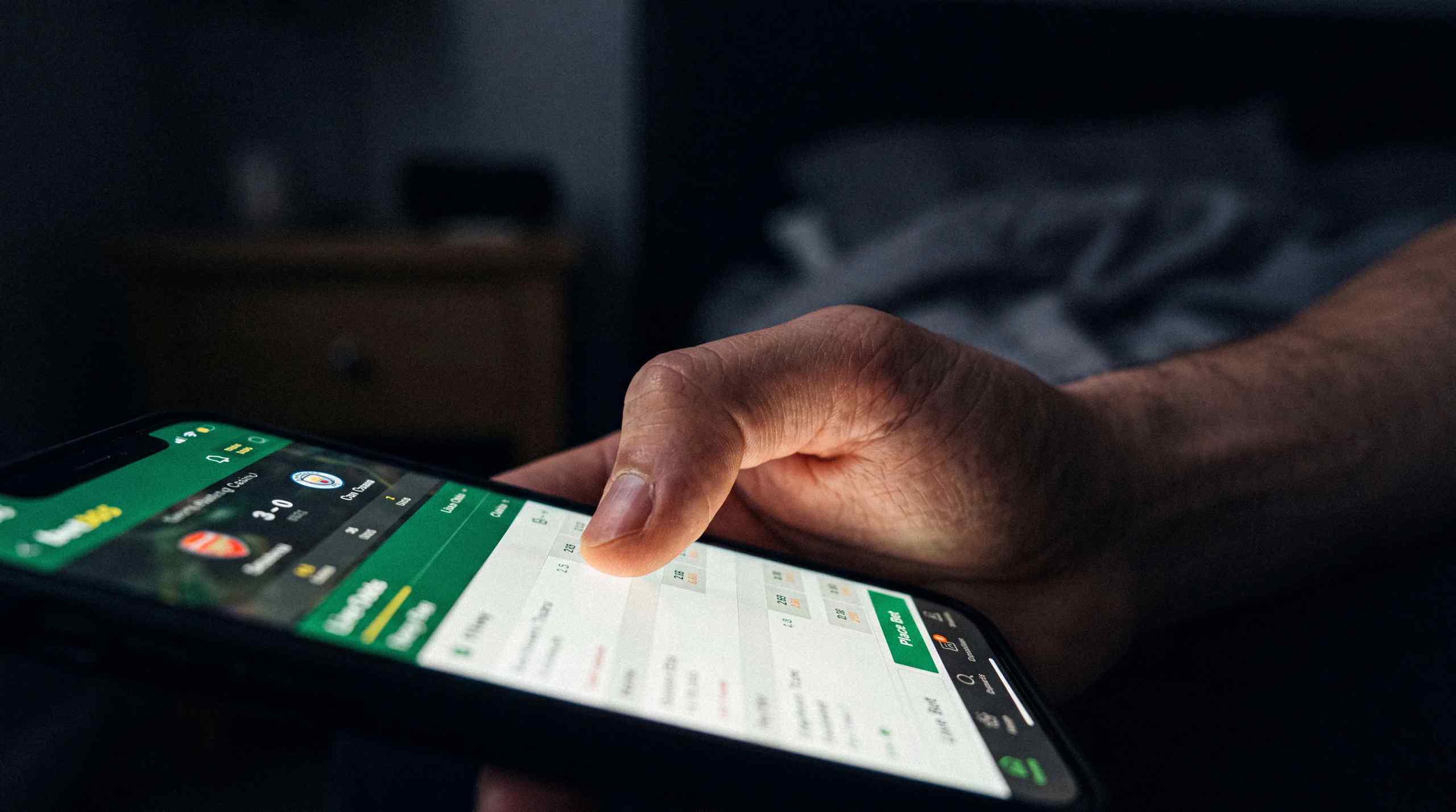 A man using an online sports betting app on his phone.